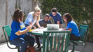 FSL的学生们坐在外面的一张桌子旁一起工作
