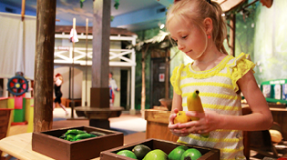 Child in Yellow Short Counting Toy Produce at the Pensacola Children's Museum