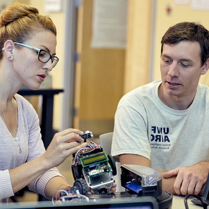 two phd students working on a robot